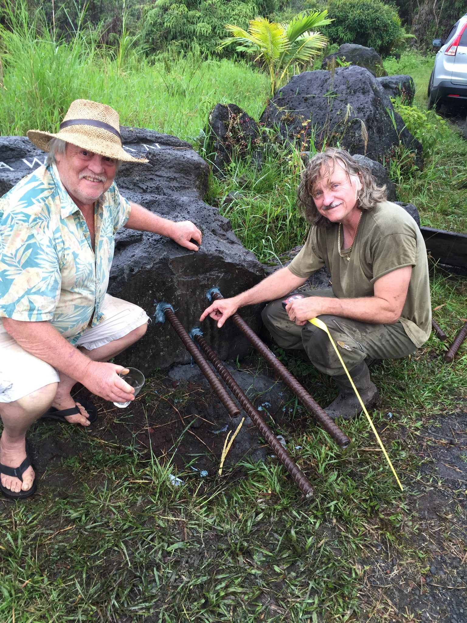 Two volunteers working on the pōhaku with hand tools